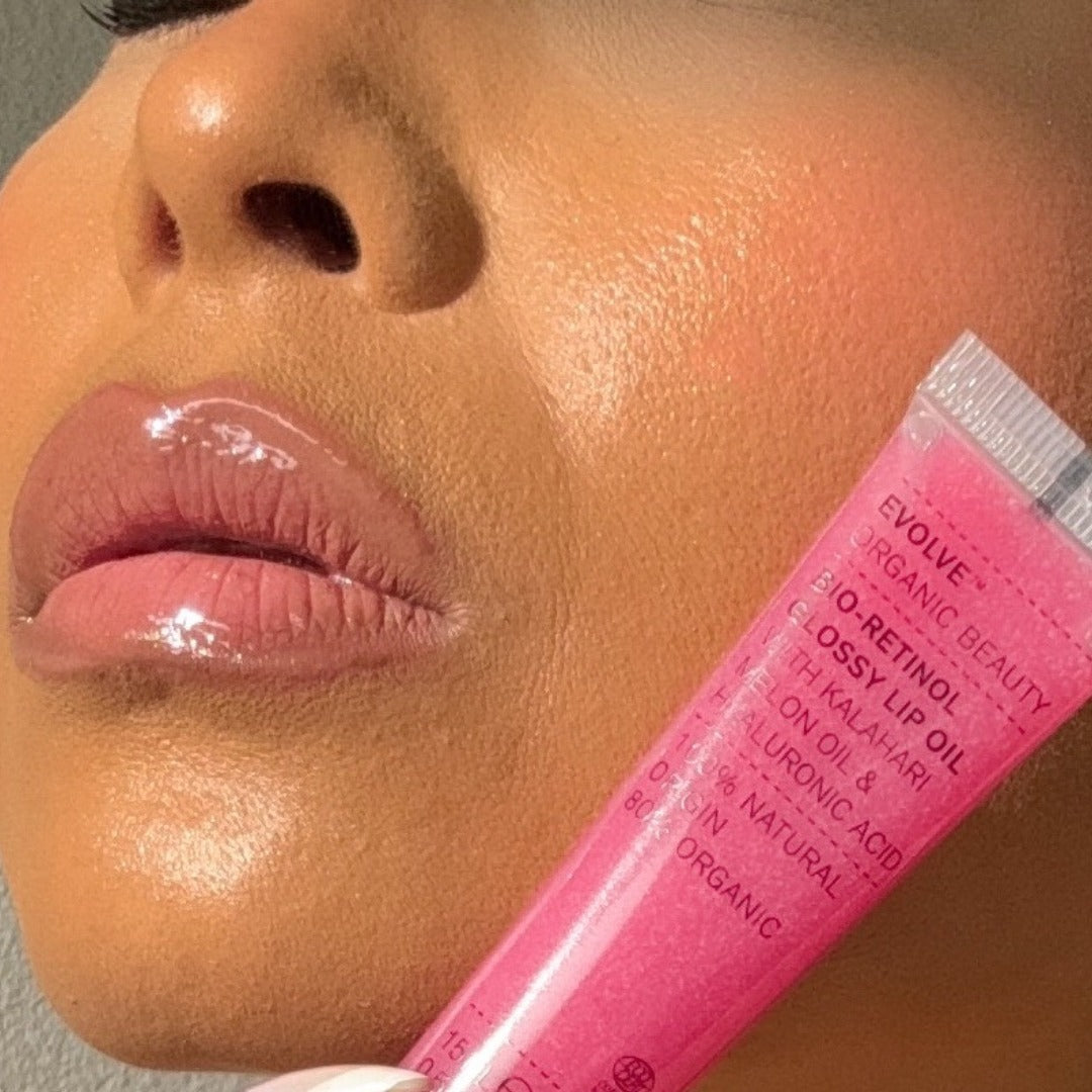 Glanzende lippen met een watermeloenroze tint, verzorgd door Evolve Bio-Retinol Glossy Lip Oil, vegan en dierproefvrij.