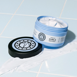 Dit vegan haarmasker van Maria Nila is geschikt voor alle soorten golven, krullen en kroeshaar. Met een mix van Shea Butter, Jojoba-olie, Aloë Vera en Vitamine E, hydrateert en conditioneert dit masker zowel het haar als de hoofdhuid, waardoor het haar zacht en gemakkelijk doorkambaar wordt zonder pluizig gevoel.